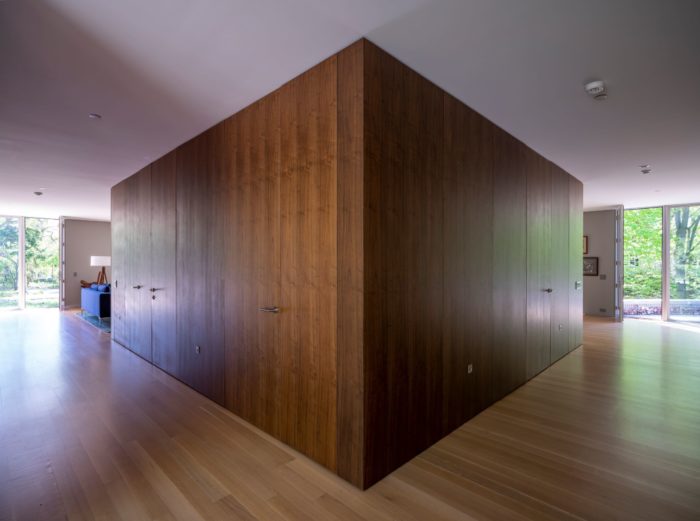At the rear of the central volume, custom veneer walnut panels conceal a laundry room on the right hand side. The left side has a powder room and storage closet. Wheeler Kearns Architect. Image credit Tom Rossiter Photography