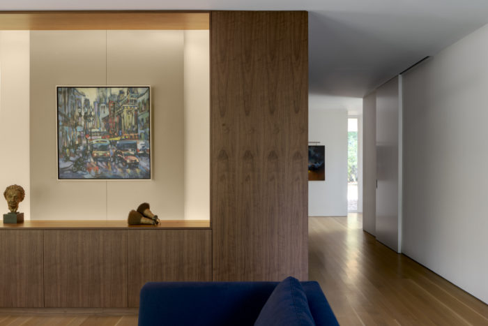 On the living room side of the central volume, a painting hangs on a floating panel which moves to conceal the television.  Wheeler Kearns Architect. Image credit Tom Rossiter Photography
